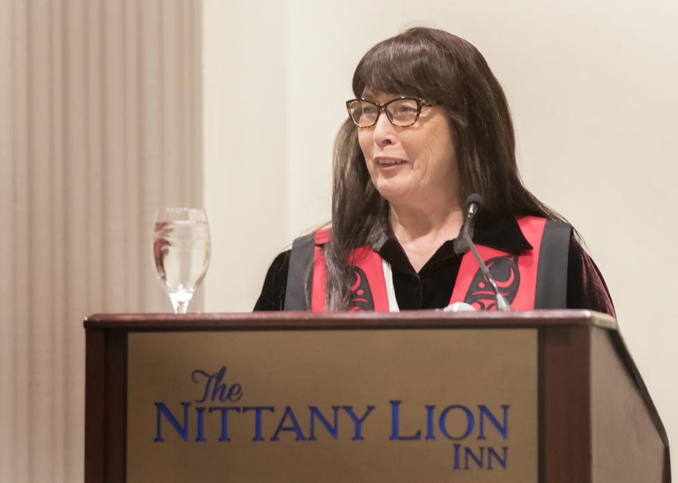 Charlene Teters speaking behind a podium at the Penn State Forum in 2018, held at the Nittany Lion Inn on the University Park campus.