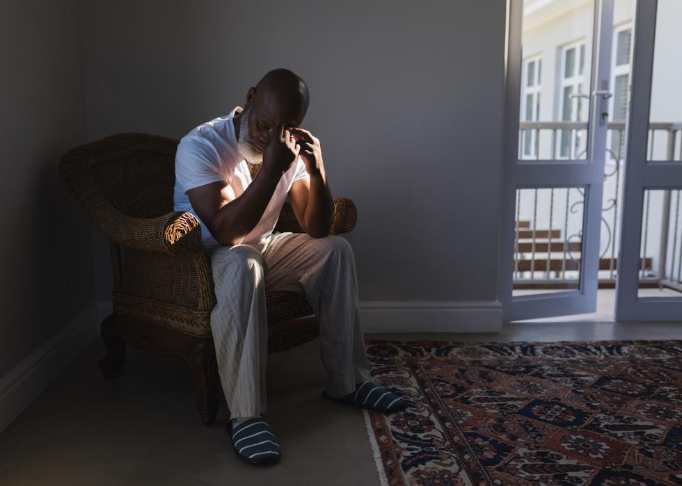 A Black senior sitting on wicker chair in their living room at home.