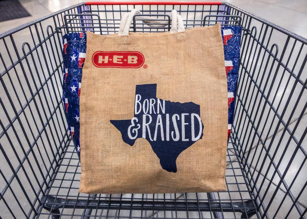 Shopping cart with H-E-B reusable shopping bag with the Texas state outline and the words 'Born and raised.'