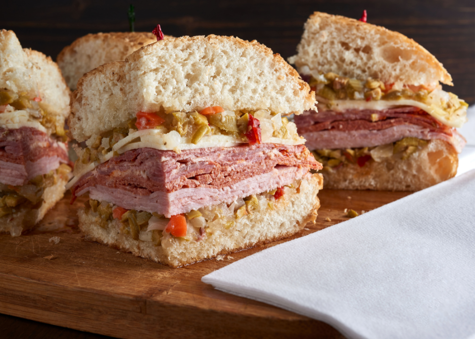 Three quarters of a muffuletta sandwich on a wooden chopping board.