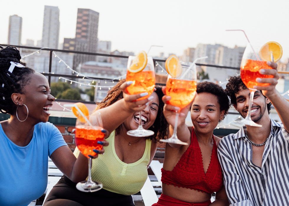 Cheerful friends enjoy colorful drinks at roof party.