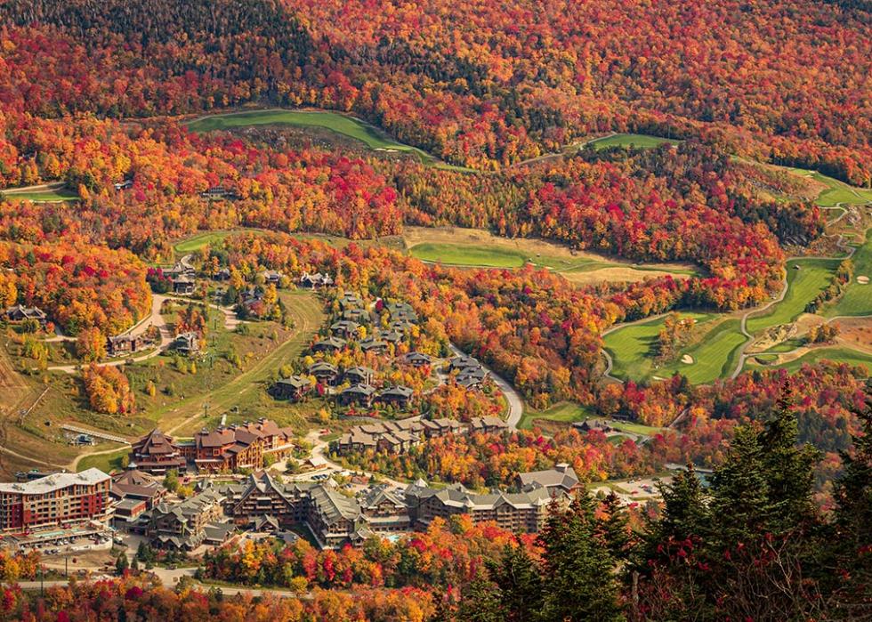 Stowe Mountain Resort in Stowe Vermont with autumn foliage around a green golf course.