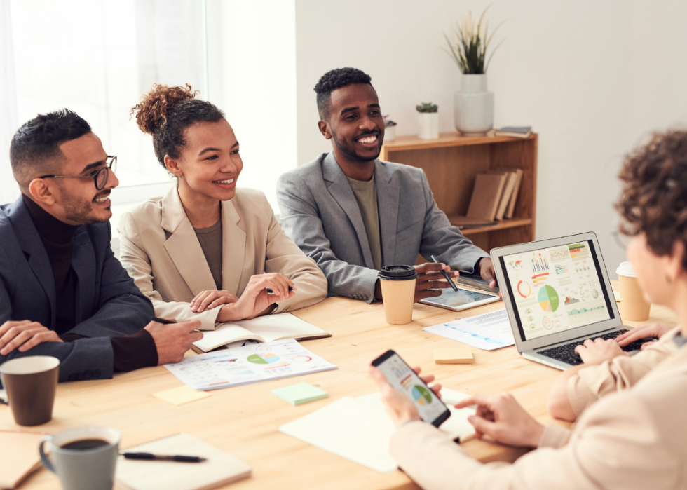 A racially and gender diverse group of young professionals sitting down together at a table.