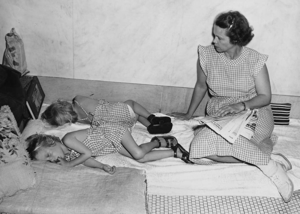 Two children sleep on the floor in the Palm Beach County Courthouse as their mother keeps watch during a hurricane in Palm Beach, Florida on August 27, 1949.