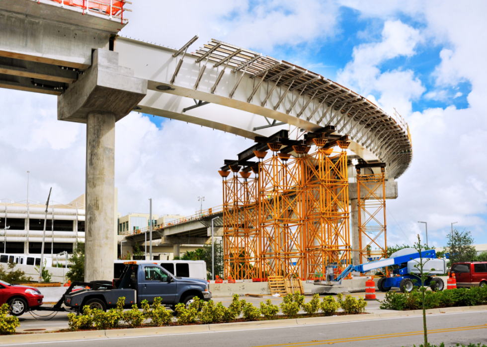 A freeway onramp sits partially built as construction scaffolding holds it up.