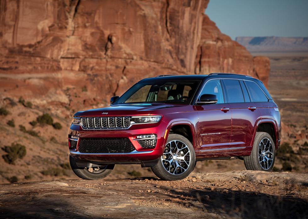 A red 2025 Jeep Grand Cherokee Summit parked on a desert road.