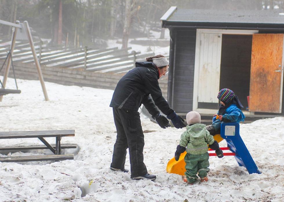 A teacher at the Turi Sletners child care program in northwest Oslo, helps children as they play in the snow. 