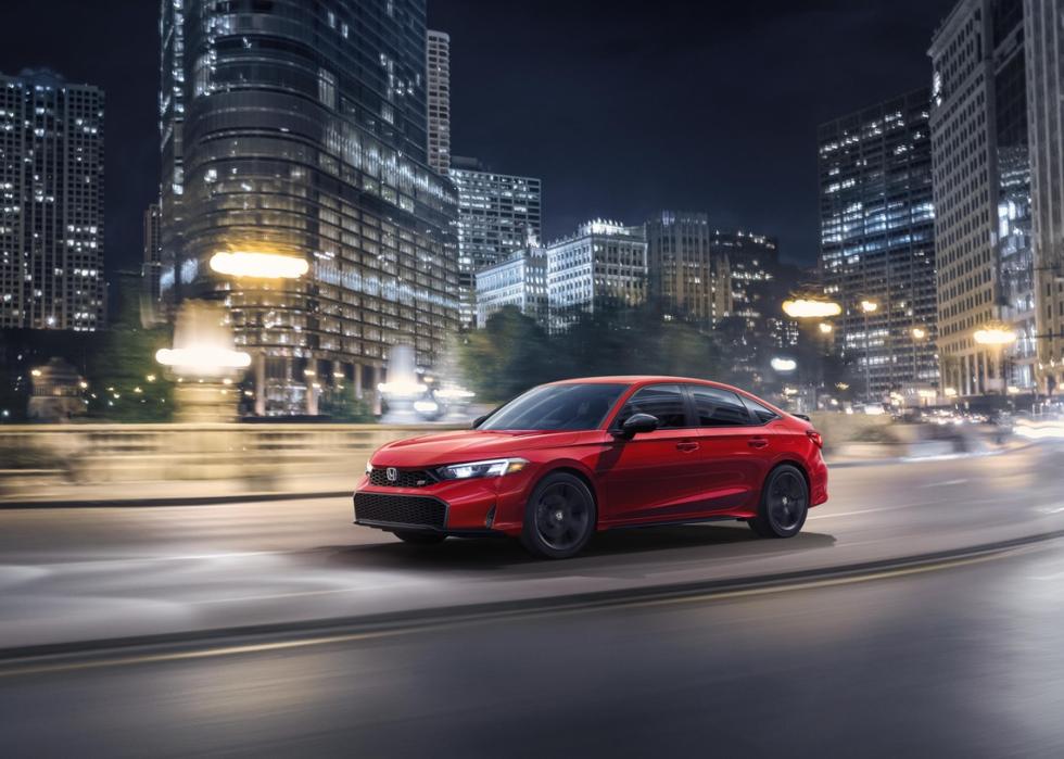 A red Honda Civic driving by a blurred cityscape.