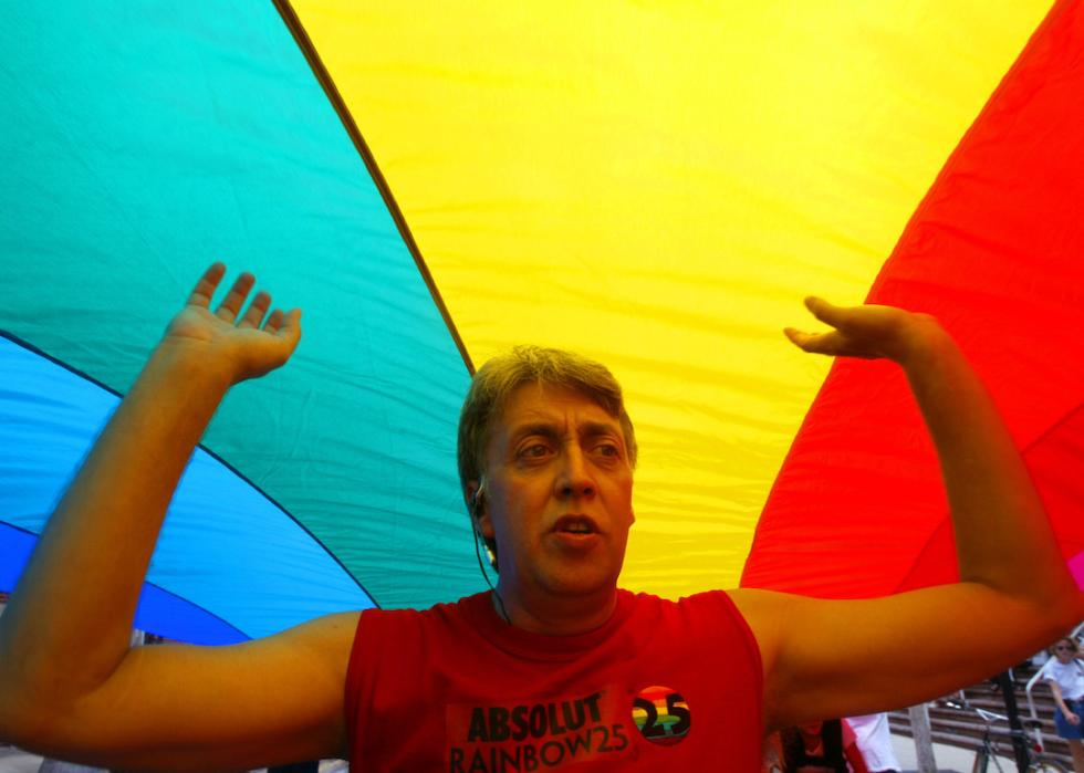 The creator of the first-ever rainbow flag twenty-five years ago, Gilbert Baker, helps stretch the mile and quarter long "World's longest Rainbow Flag" on June 15, 2003.