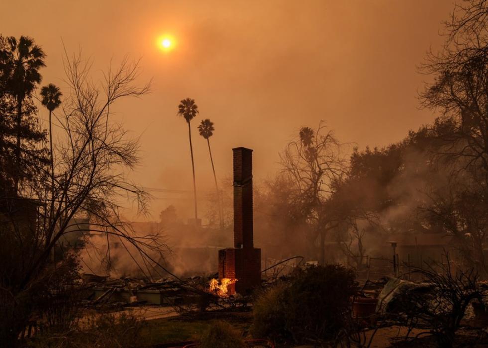 A brick chimney remains while the surrounding area of a home still burns during the Eaton fire.