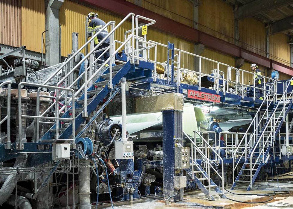 House-sized machines shred old clothes and textile remnants in a recycling facility.