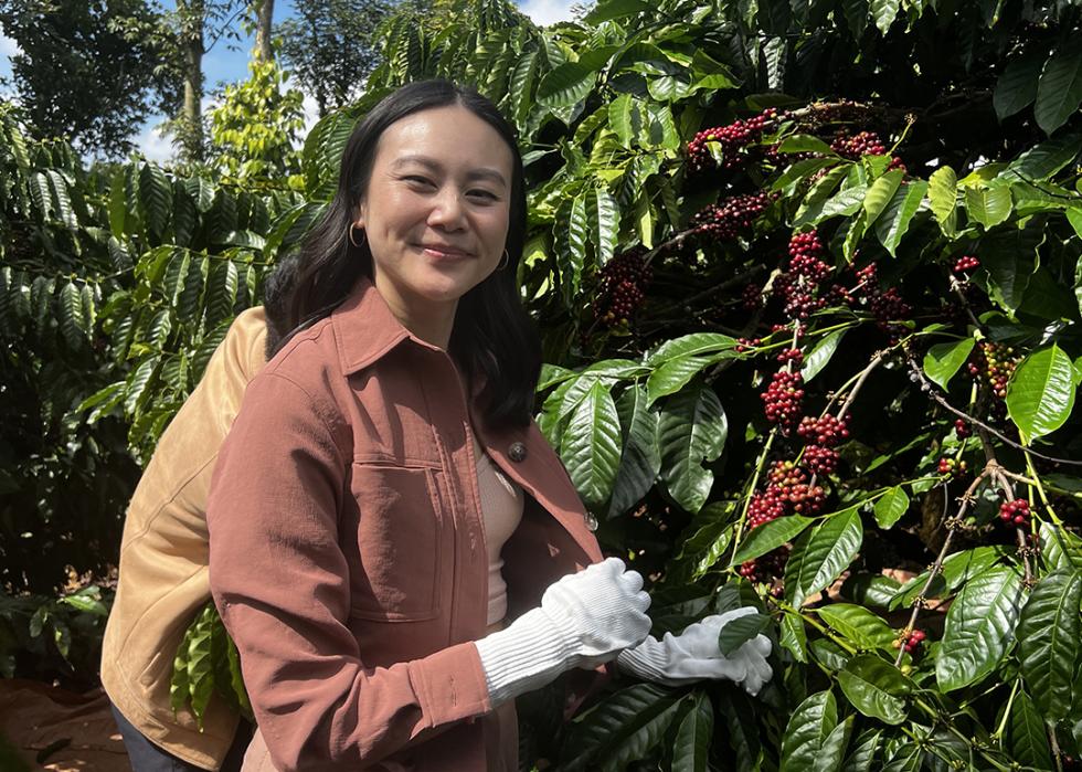 Nguyen Coffee Supply founder, Sahra Nguyen, posing for a photograph while harvesting robusta coffee.
