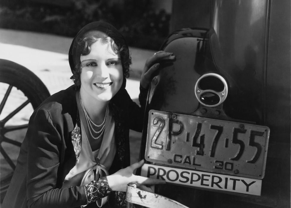 Woman with prosperity sign on car bumper.
