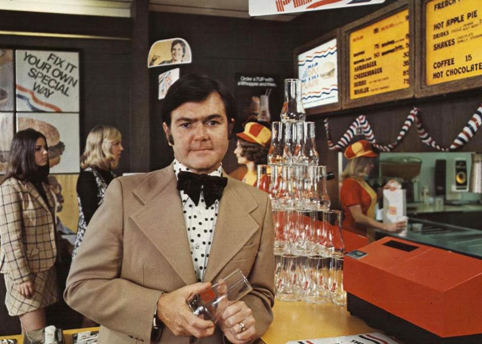 A man in a suit holding a glass inside of a Burger King