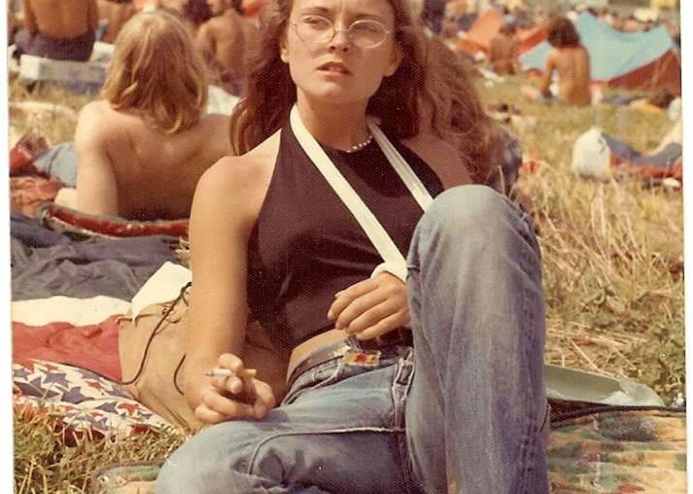 A young woman with her arm in a sling laying in a field at a concert