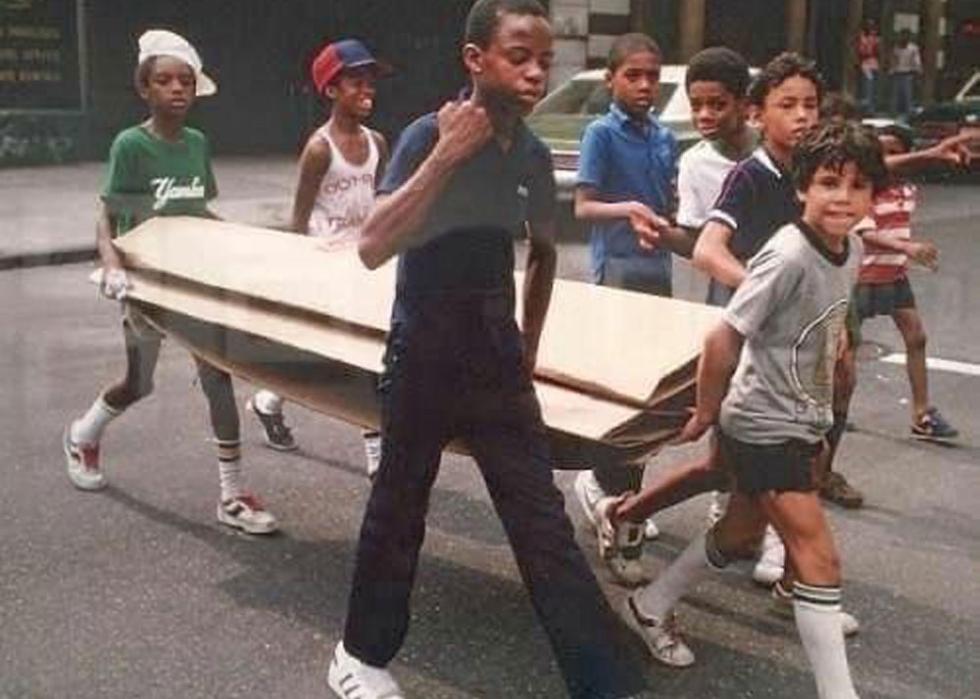 Group of kids carrying a large amount of cardboard across a street
