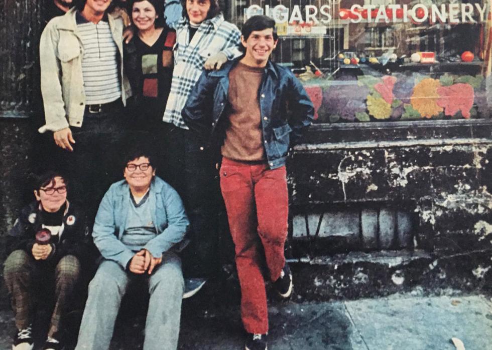 A group of kids stand and sit in front of a candy store