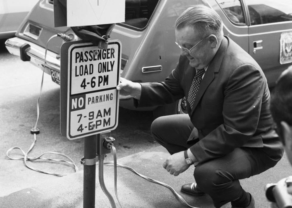 Man kneeling next to a sign that reads Electro Park while charging his car