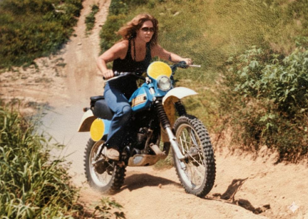 A woman riding up a steep hill on a dirt bike