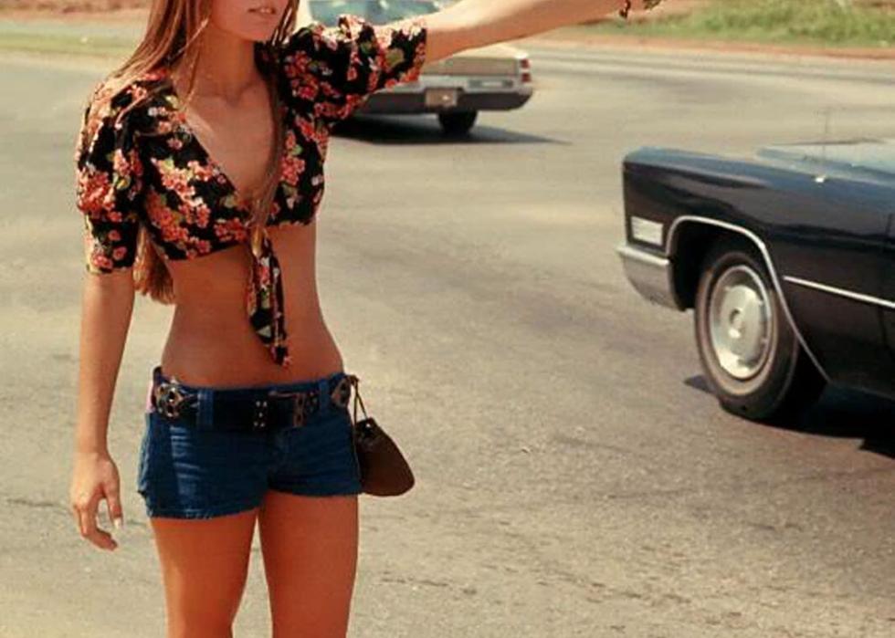 Young woman selling flowers, barefoot, on the side of the road