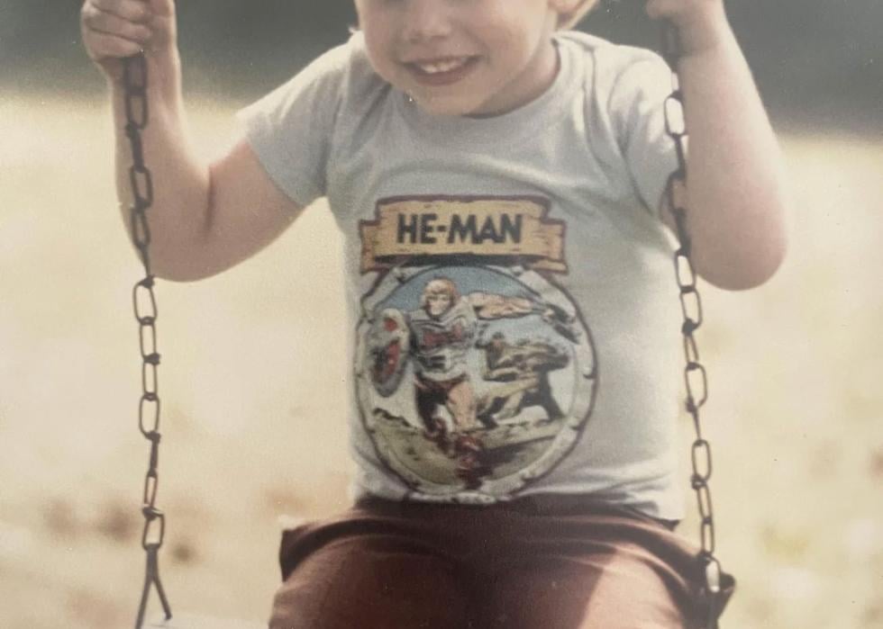 Little boy wearing a He-Man shirt on a swing