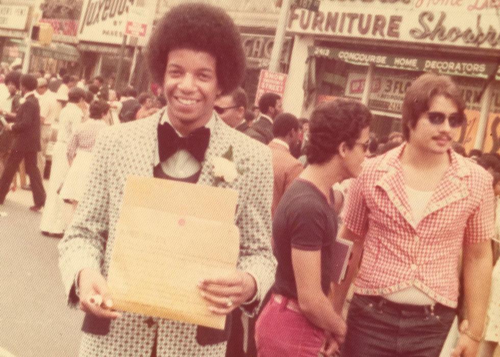 A man in a suit smiling with his diploma 
