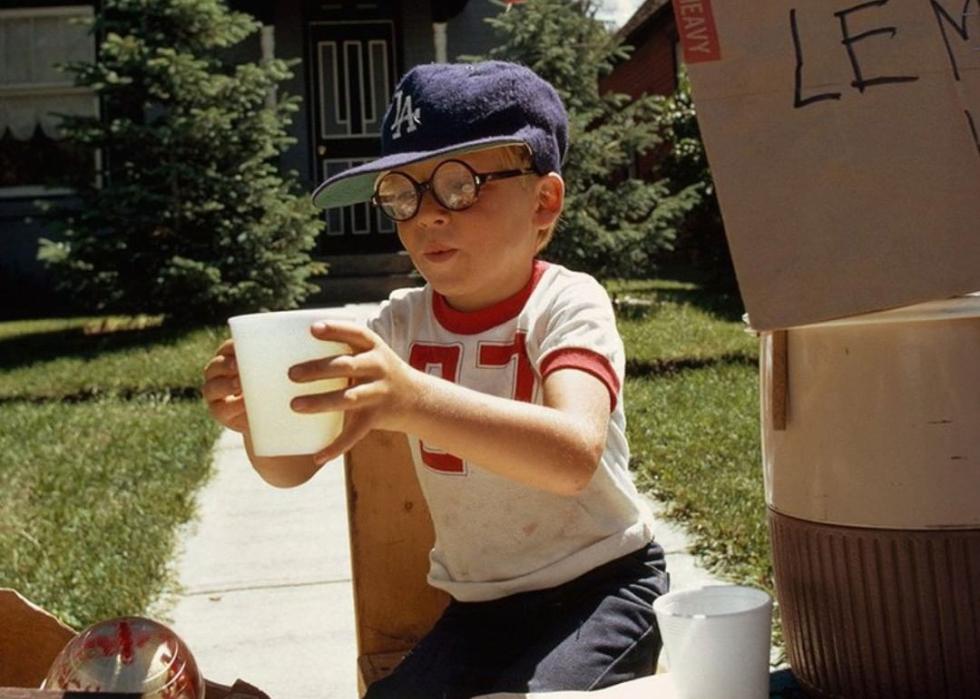 A boy wearing a Dodgers ball cap selling lemonade in his front yard