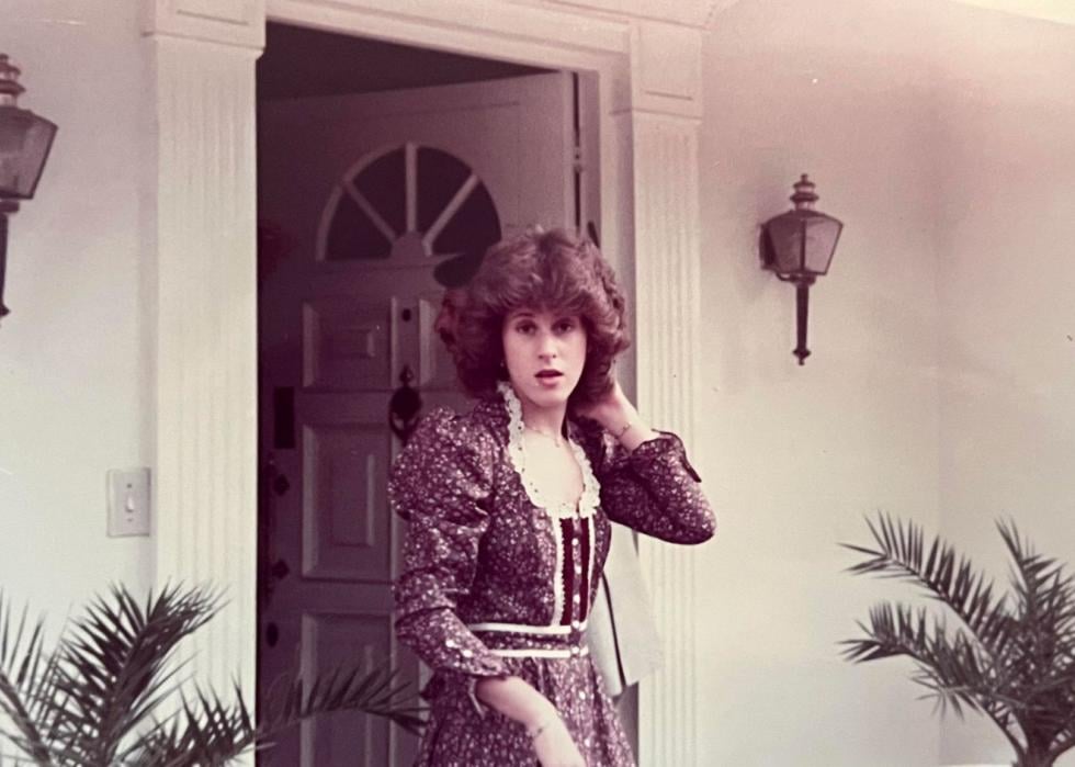 A woman wearing a very 80s dress headed out the front doorb