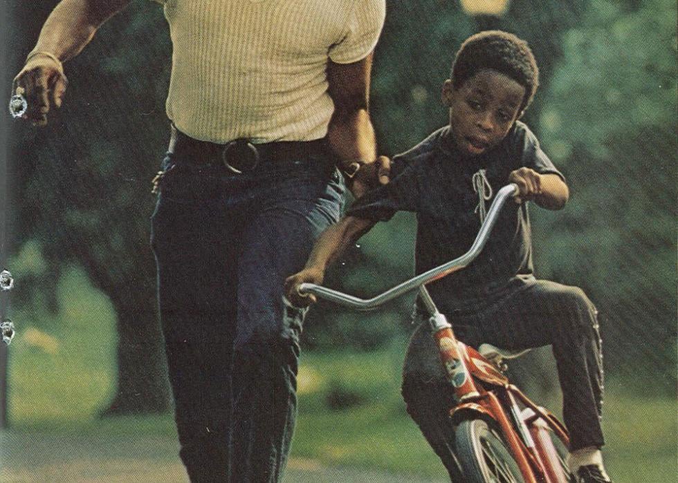 Father holding onto his sons arm as he learns how to ride a bike