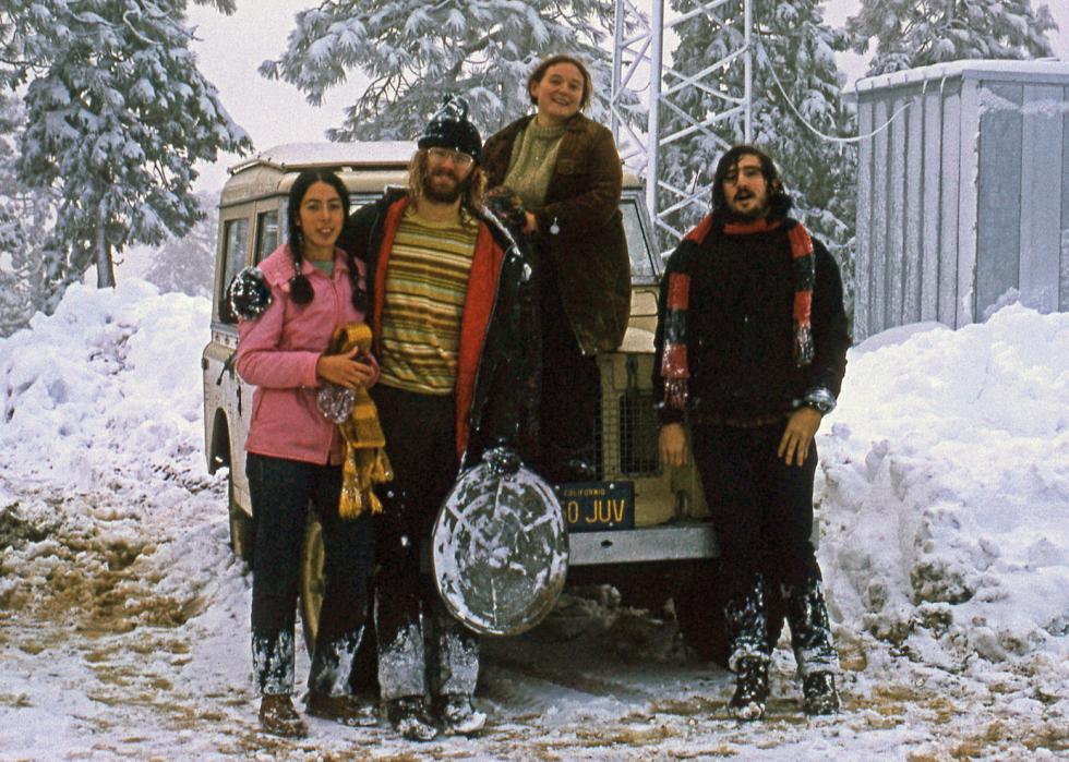 Four friends standing around in the snow 