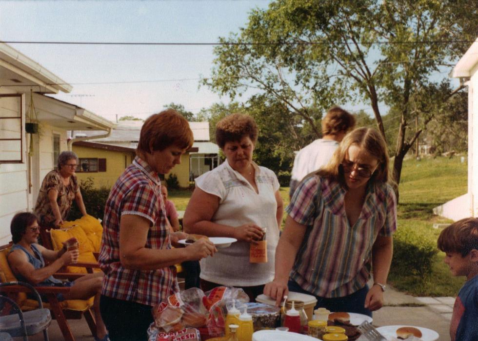 A family hanging out in a backyard, preparing some hamburgers