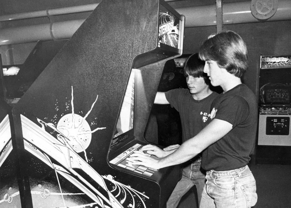Black and white photo of kids playing an Asteroids arcade game in 1981