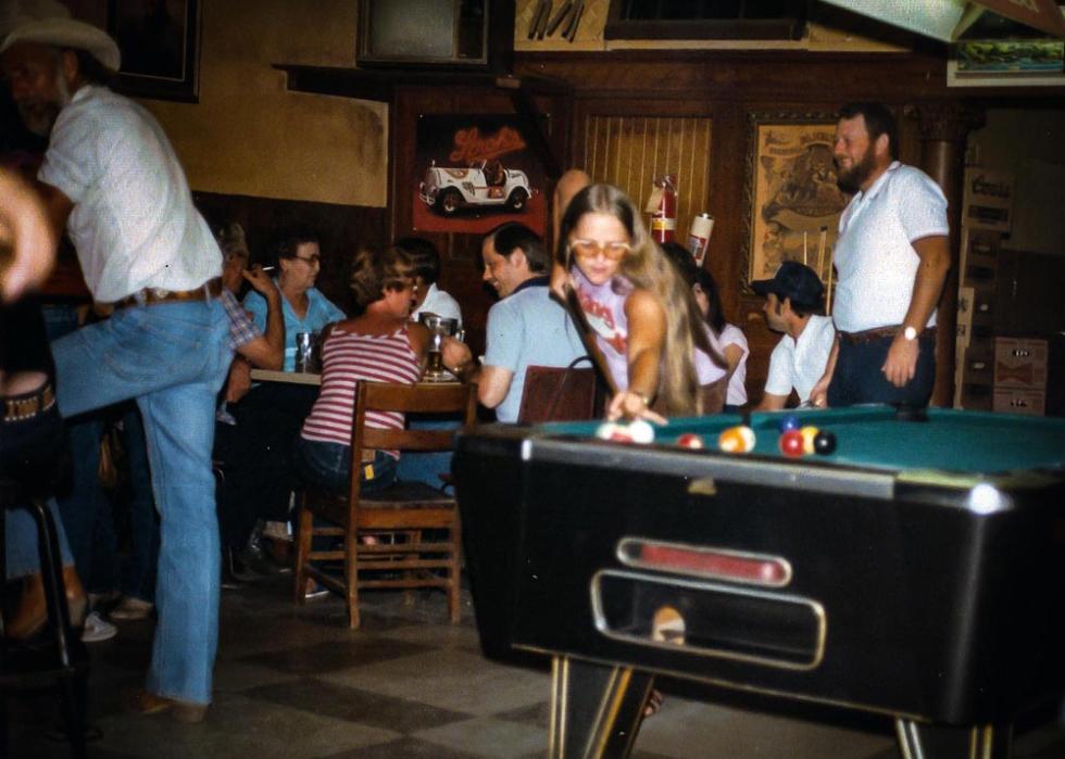 Woman playing pool in a fairly busy bar