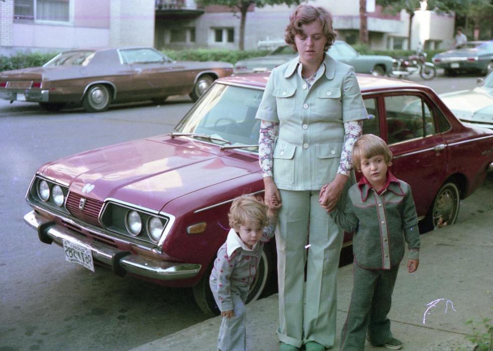 Two kids with their mother on the sidewalk dressed in very 1970s clothes