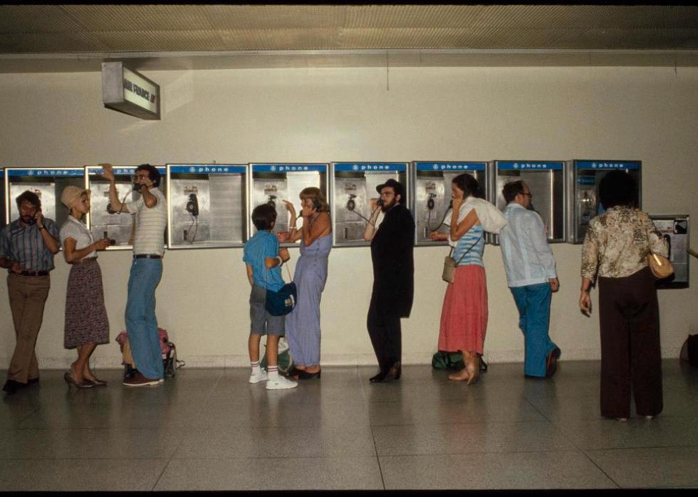 Various people talking on a wall of payphones at LaGuardia airport
