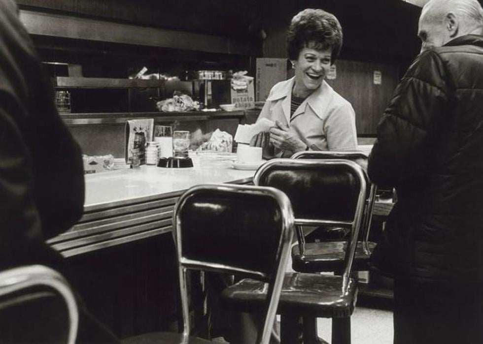 Black and white photo of a waitress laughing