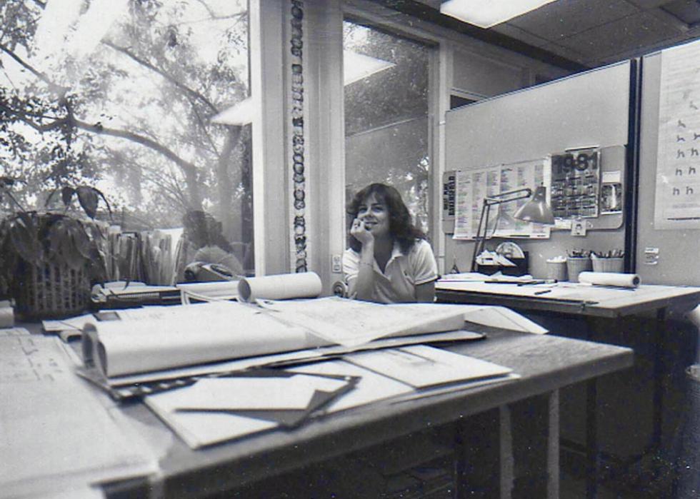 A young woman sitting at a desk looking at the camera