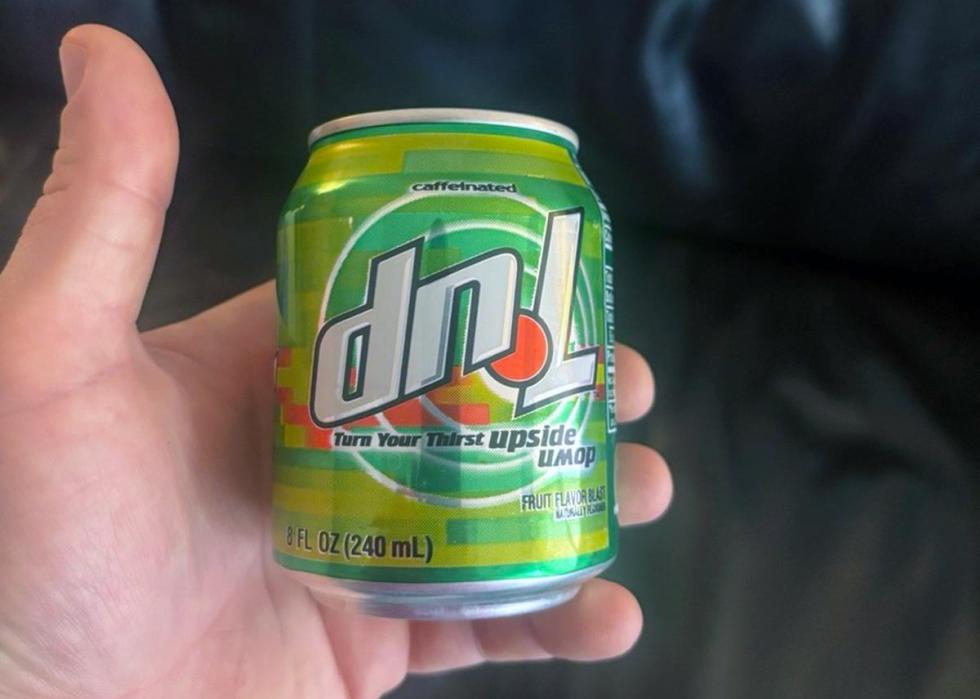 A hand holding a small can of dnL soda.