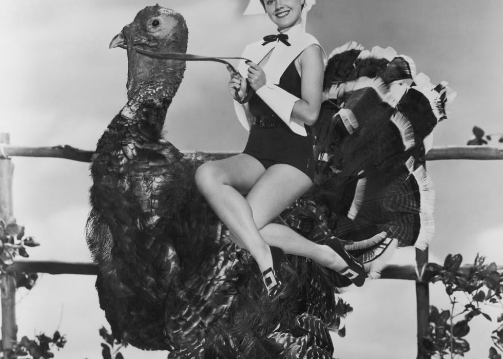 American actress Virginia Gibson, in a glamorous version of puritan costume, rides a giant Turkey, circa 1952.