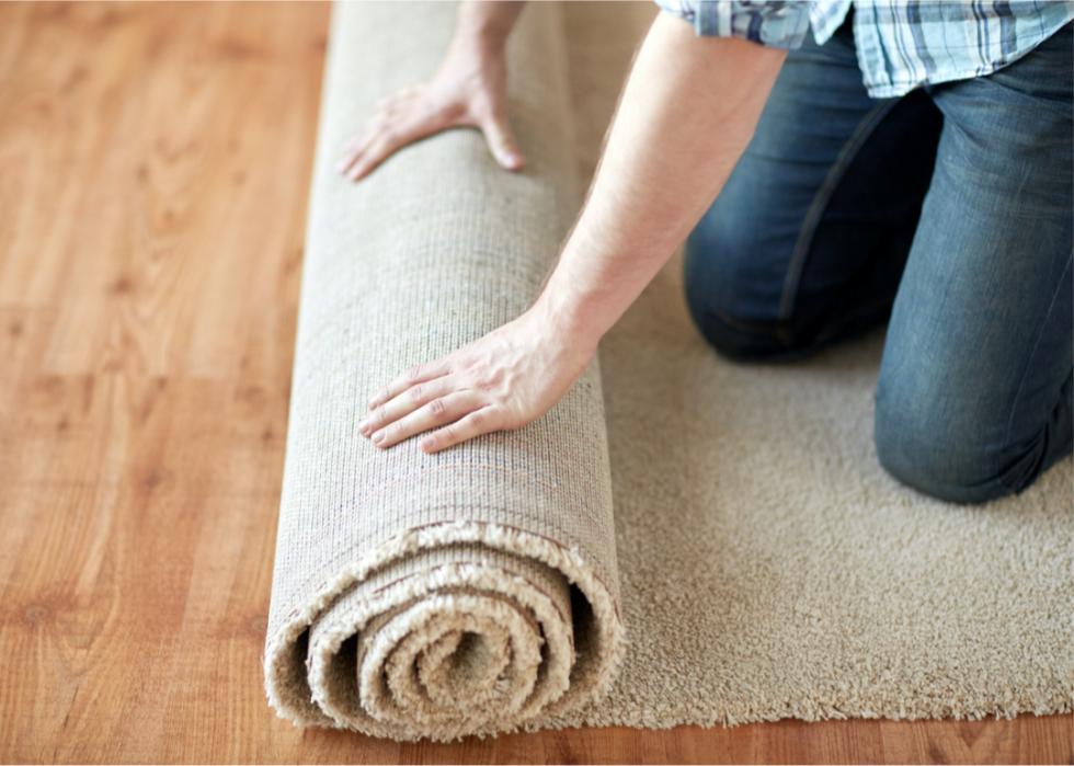 Photo shows a close-up of a person rolling up a carpet