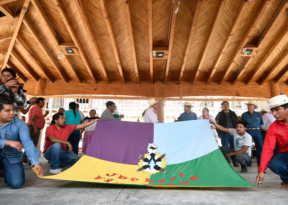 twelve members of the recently elected Purepecha indigenous council, display a Purepecha flag.