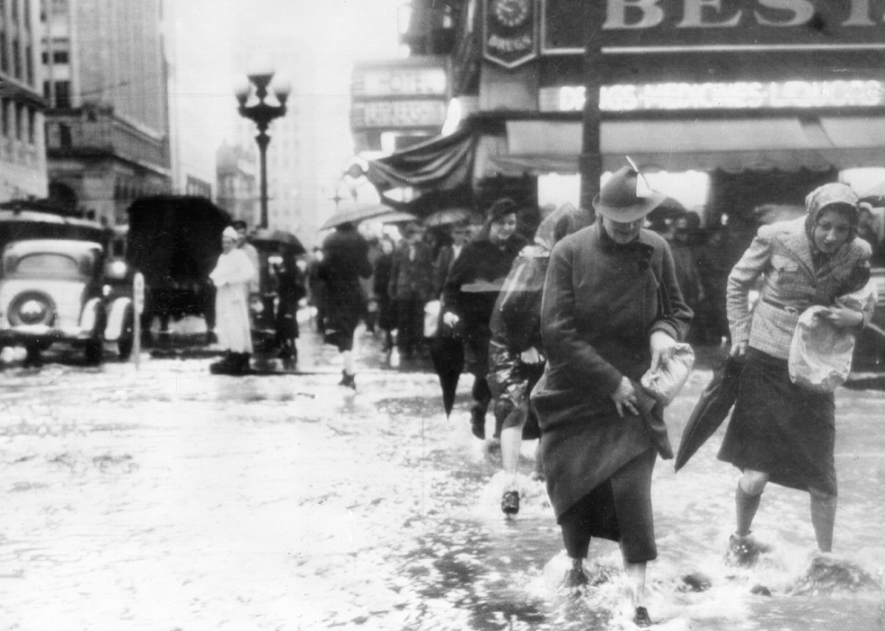 People walking through ankle-deep water along an urban street.