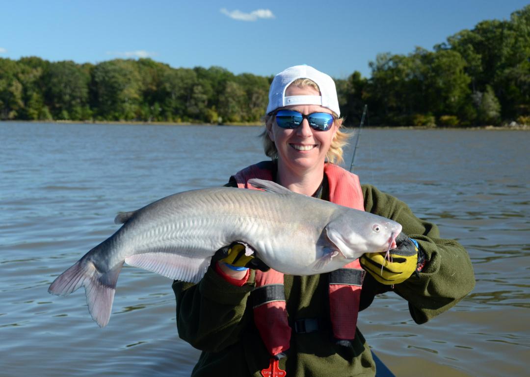 blue catfish fish being held horizontally by a smiling person.