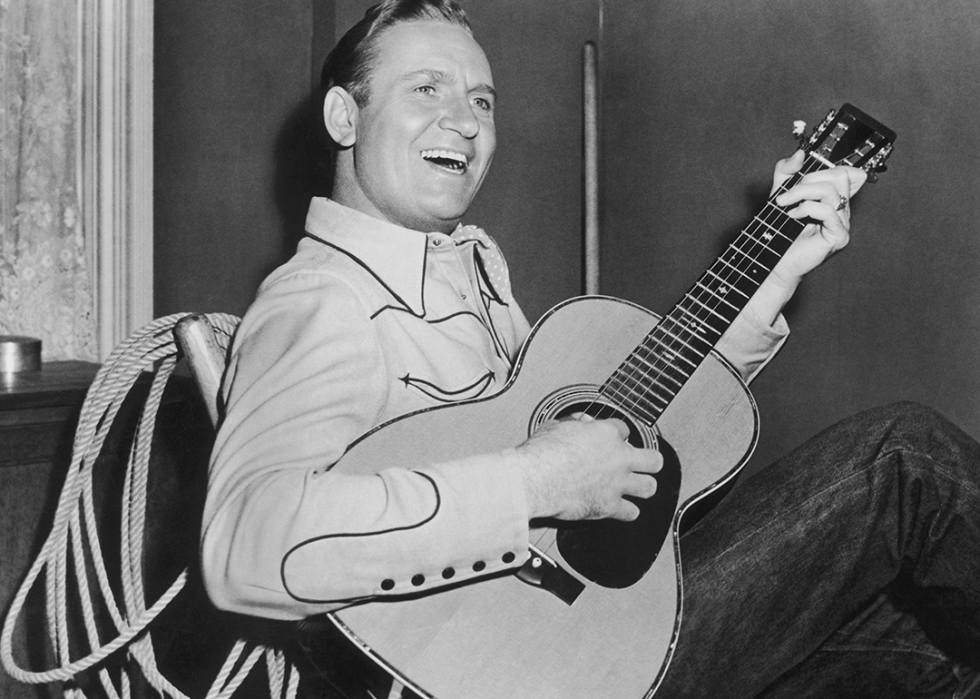 Gene Autry posed in a chair with guitar.