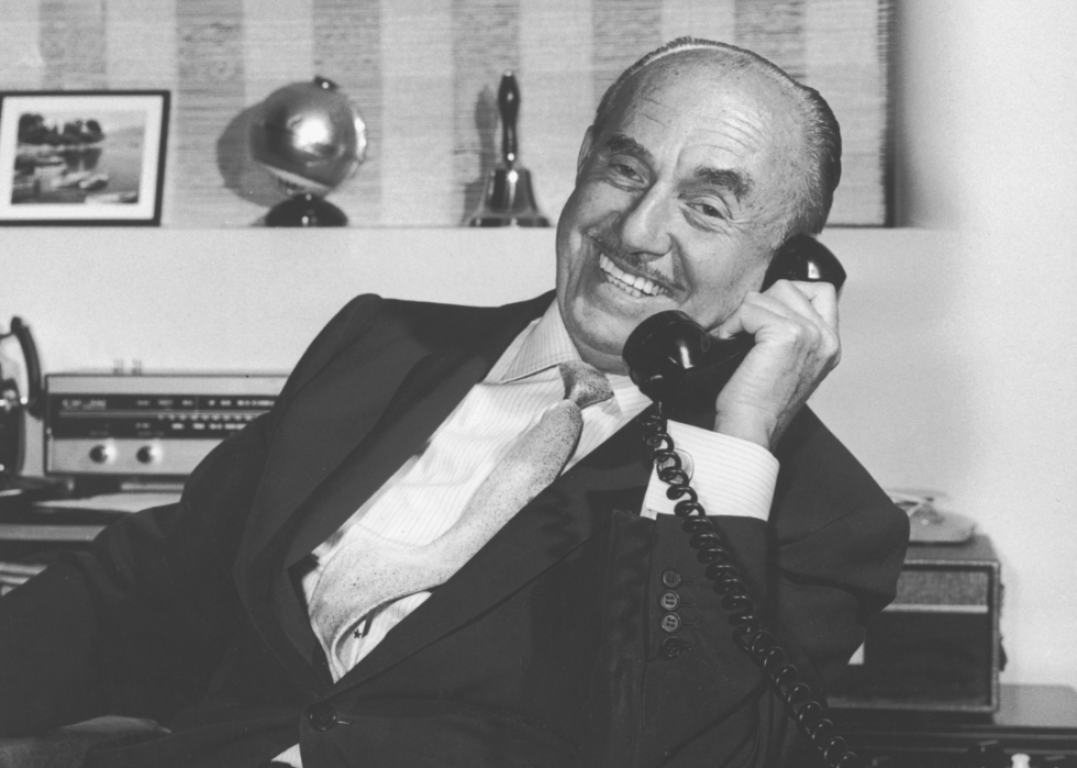 Jack L. Warner smiles holding a phone.