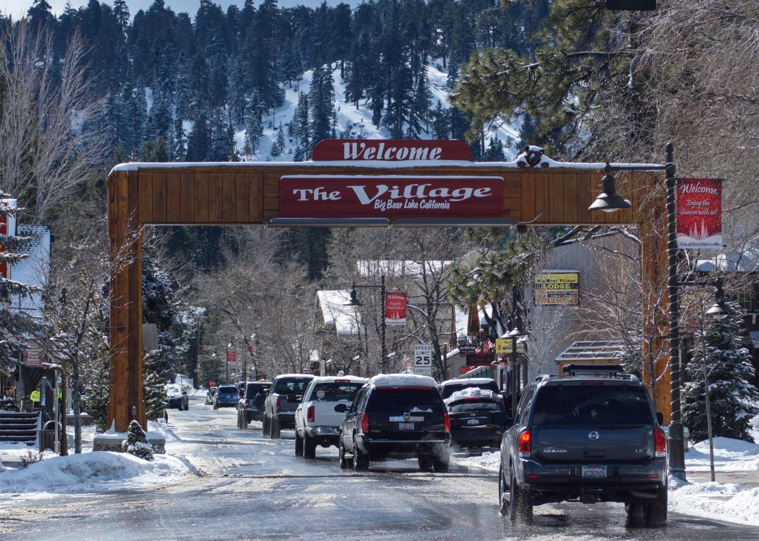 Cars driving under Welcome to Big Bear village sign in winter