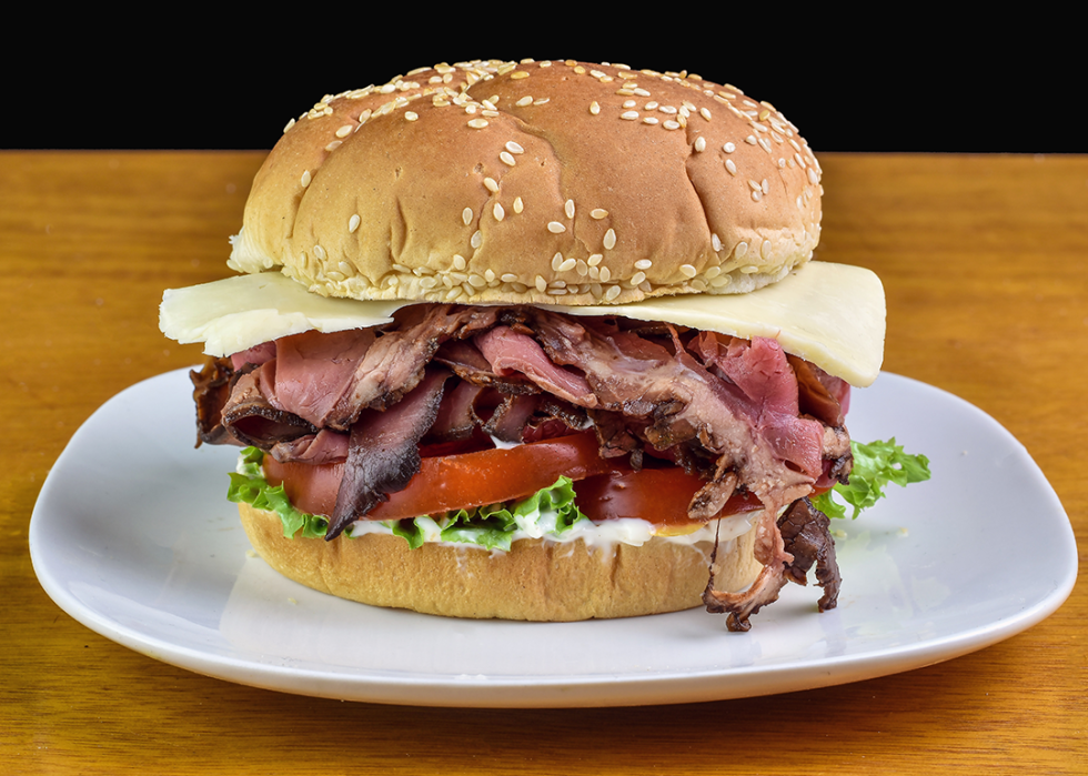 Roast beef sandwich with tomatoes and Swiss cheese on a sesame bun.