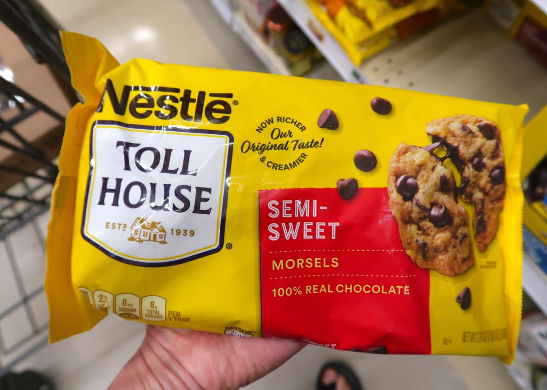 Hand holding bag of Nestle Toll House semi-sweet chocolate chips.