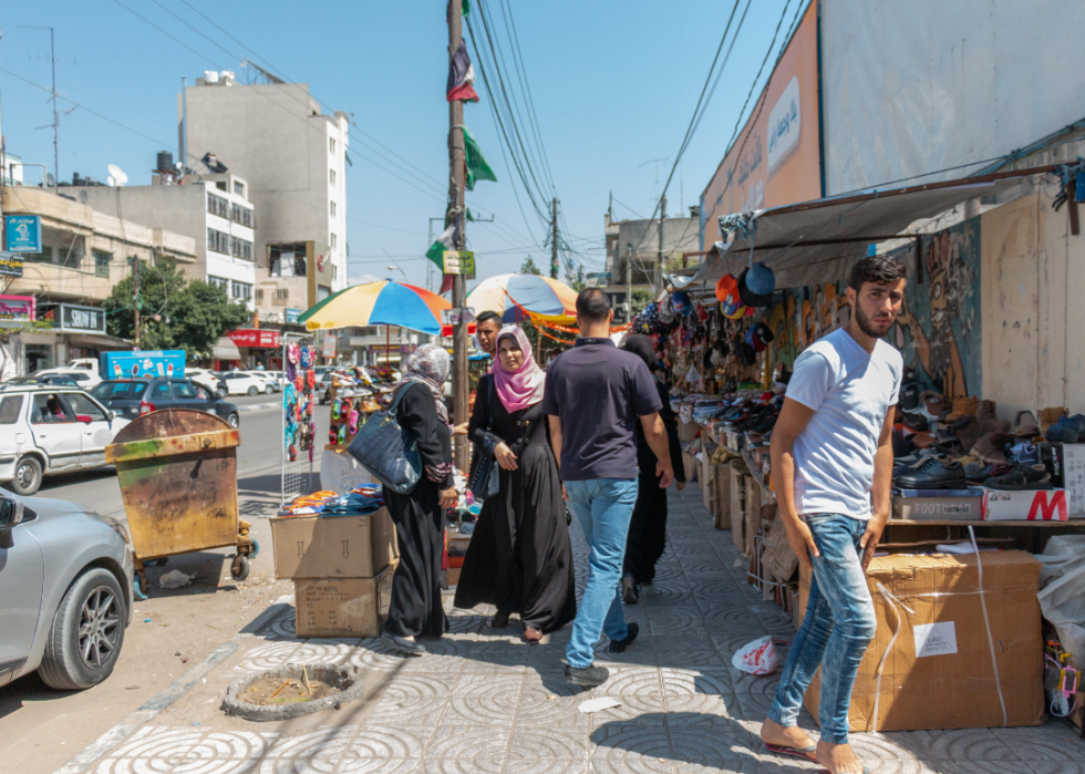 People walking on busy street with market stalls in Gaza