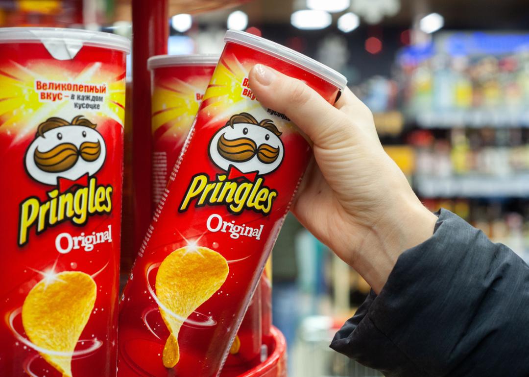 Hand holding package of Pringles potato chips.